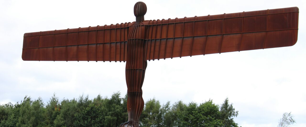 Massive sculpture in the form of an angel made from weathering steel.